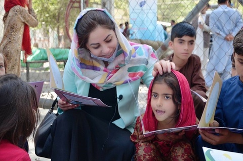 Qaderi reads with young children in a public setting.