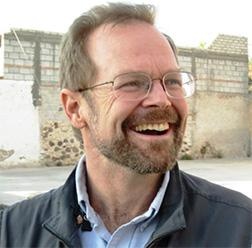 A portrait of Christopher Merrill smiling and looking to the right