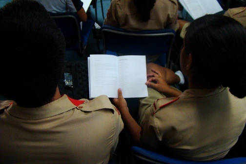 Some students read through a program.