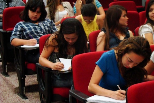 A group of students sit in chairs taking notes.