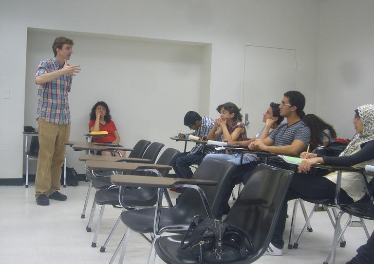 Hugh Ferrer leads a discussion before a room of students sitting in desks.