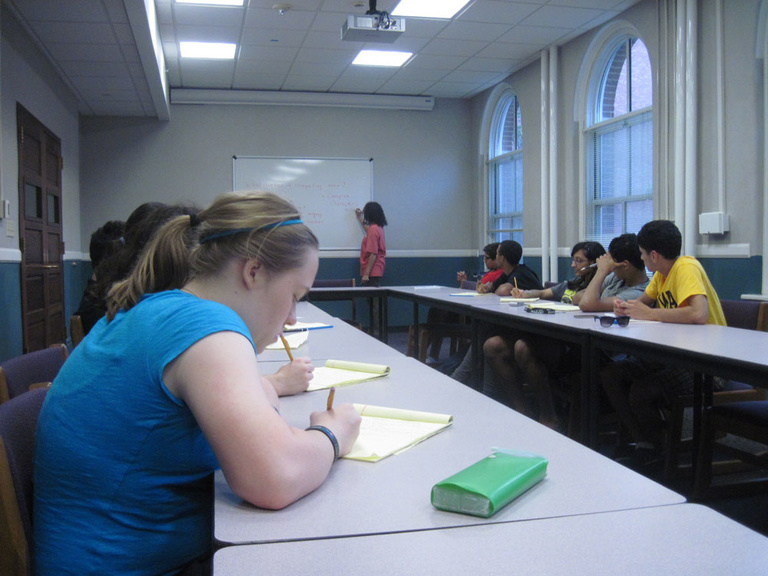 A group of Between the Lines participants sit at desks, working on playwriting.