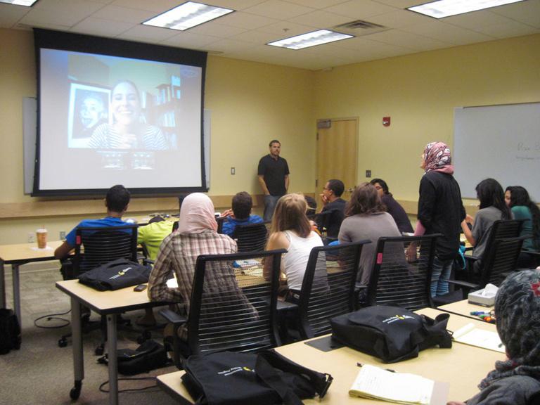 Between the Lines participants sit at desks and watch poet Rae Bryant present via Zoom.