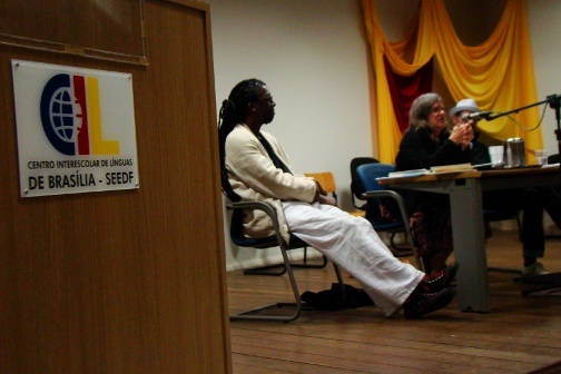 Three people present on a stage at the Centro Interescolar de Linguas