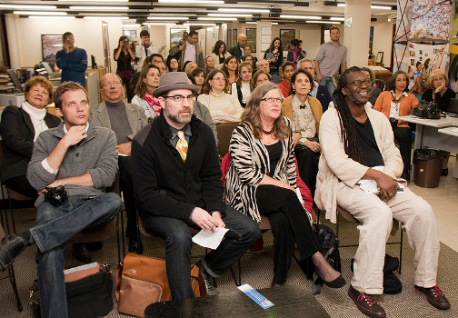 A group of people sit in a room and watch a jazz performance.