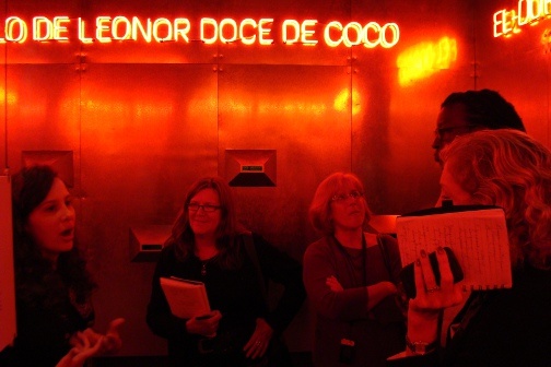 A group of people stand around talking in a red lit room.