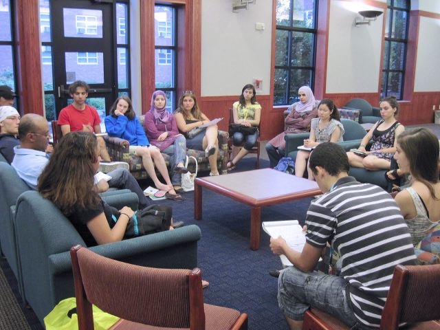 Students sit in a circle and discuss forms of Arabic and English poetry.