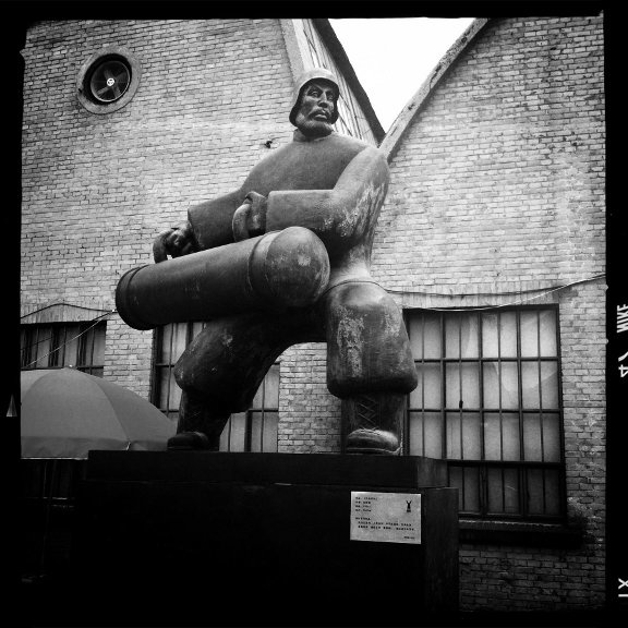 Public art in Beijing's 798 Art Zone - a statue of a man carrying a cylindrical object with both hands.