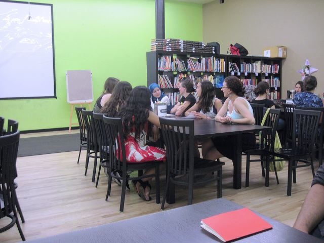 Between the Lines participants sit at a table writing and designing children's books at 826 Chicago.