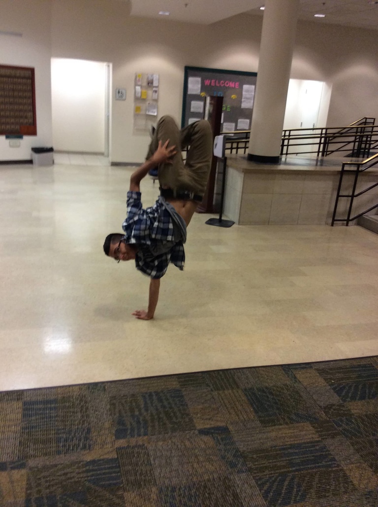 A Between the Lines participant breakdances in the common area of a dormitory.