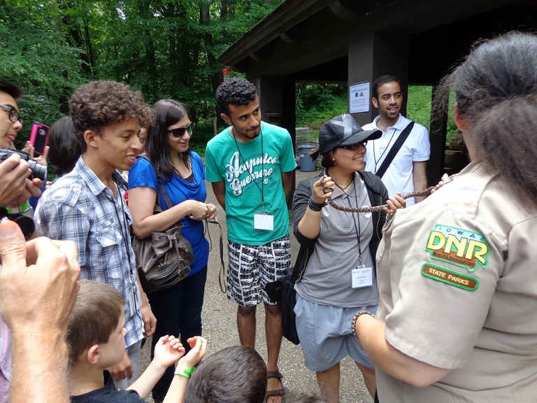 A group of Between the Lines participants learn about snakes from a member of the Iowa DNR.  One participant holds a snake.