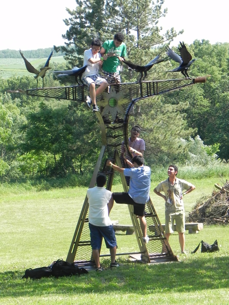 A group of Between the Lines participants climb on a metal statue.