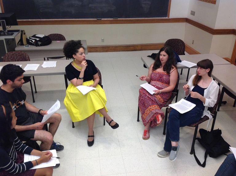  A group of Between the Lines participants sit in a circle holding papers and having a discussion.