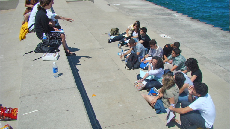 Instructors Anjali Sachdeva and Daniel Khalastchi lecture outdoors at the Museum Campus to students who sit listening.