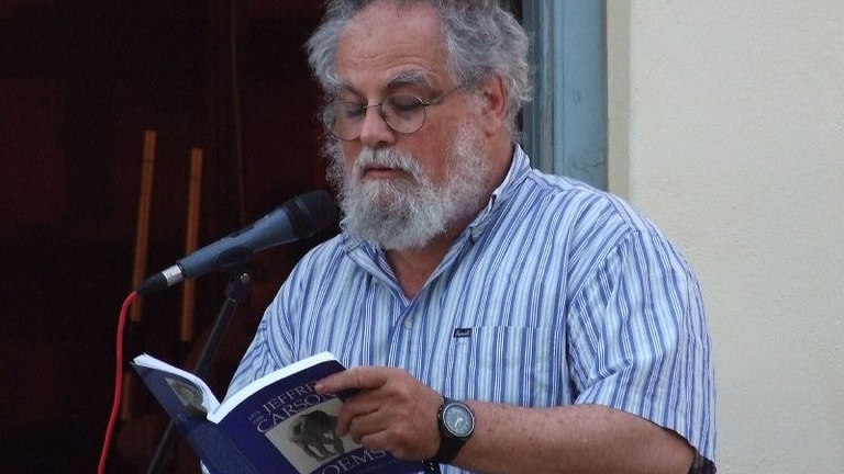 A man reads from a book into a microphone.
