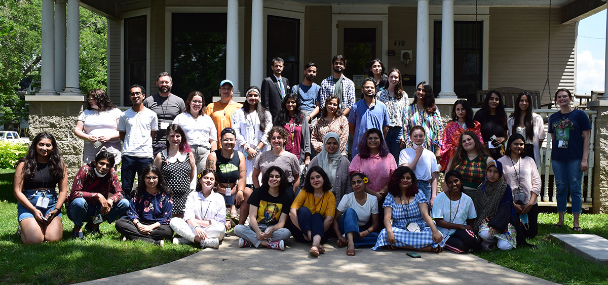 A group photo from the Summer Institute; students sit together outside with program staff, in front of the Shambaugh House.