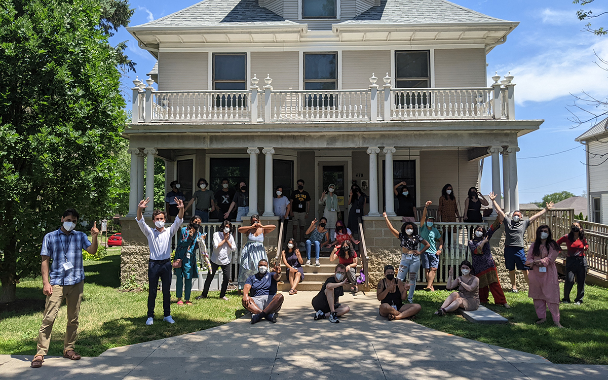 Another group photo from the program; in this one, students stand or sit in front of the Shambaugh House or on the porch, doing "silly" poses.